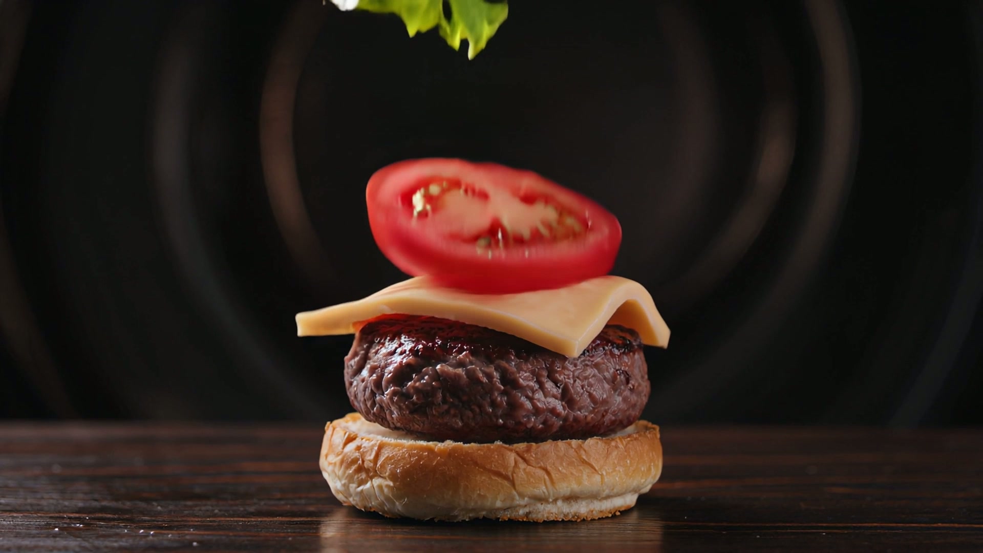 Close-up slow motion of a gourmet burger stack being assembled, ingredients falling in midair, lettuce, tomato, patty, cheese, landing perfectly. Dramatic lighting, high detail, 4K food cinematography.